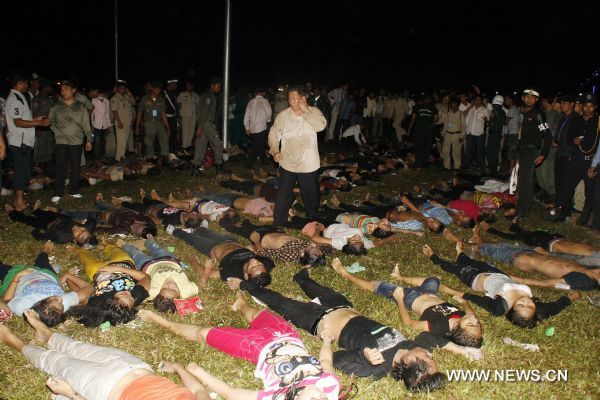 People stand near the bodies of the stampede victims in Phnom Penh, Cambodia, Nov. 23, 2010. At least 339 people were killed in a stampede on Monday night as millions of Cambodians celebrated the annual water festival in the capital Phnom Penh, Cambodian Prime Minister Hun Sen said on state TV early Tuesday. The accident took place on a bridge that connects the city with the Diamond Island which has become the center of celebrations. [Xinhua/Phearum]