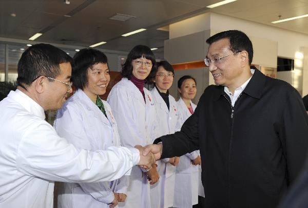 Chinese Vice Premier Li Keqiang (R), also a member of the Standing Committee of the Political Bureau of the Communist Party of China (CPC) Central Committee, shakes hands with the working staff during his visit to the Chinese Center for Disease Control and Prevention (China CDC) in Beijing, capital of China, on Nov. 22, 2010. Li visited the center on Monday, prior to World AIDS Day which falls on Dec. 1. [Rao Aimin/Xinhua]