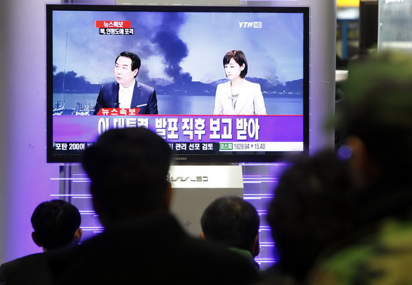 Residents in the ROK watch the news on television showing smoke rising from Yeonpyeong Island after it was hit by dozens of artillery shells fired by the DPRK, at Seoul railway station Nov 23, 2010. [China Daily/Agencie]