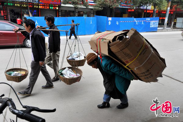 Tan Xiaozhen, 100, carries almost 40kg&apos;s waster paper to salvage station for selling on November 17, 2010 in Guiyang, Guizhou province of China. [CFP]