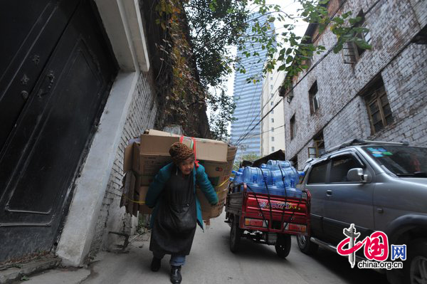 Tan Xiaozhen, 100, carries almost 40kg&apos;s waster paper to salvage station for selling on November 17, 2010 in Guiyang, Guizhou province of China. [CFP]