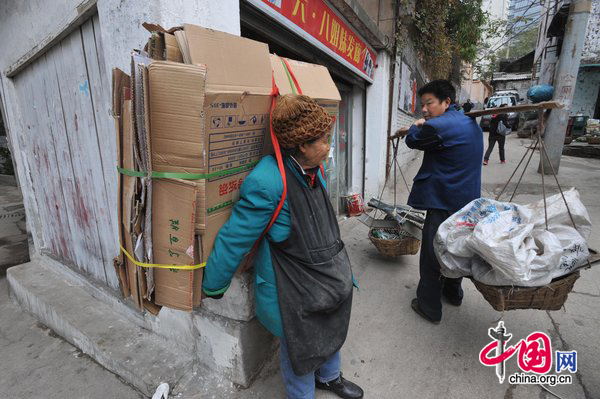 Tan Xiaozhen, 100, carries almost 40kg&apos;s waster paper to salvage station for selling on November 17, 2010 in Guiyang, Guizhou province of China. [CFP]