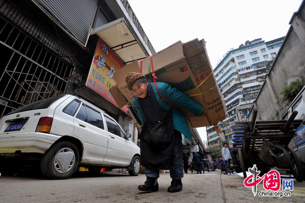 Tan Xiaozhen, 100, carries almost 40kg&apos;s waster paper to salvage station for selling on November 17, 2010 in Guiyang, Guizhou province of China. [CFP]