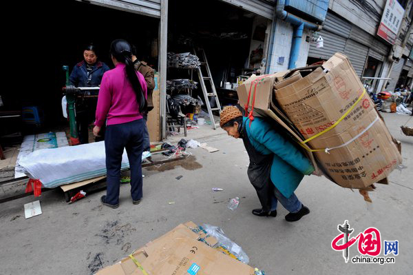 Tan Xiaozhen, 100, carries almost 40kg&apos;s waster paper to salvage station for selling on November 17, 2010 in Guiyang, Guizhou province of China. [CFP]