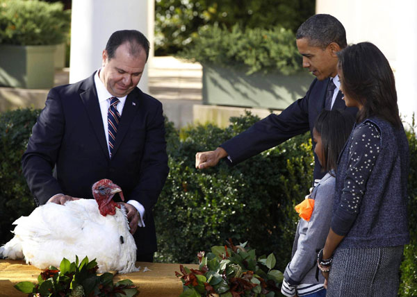US President Barack Obama (2nd L) pardons the National Thanksgiving Turkey next to National Turkey Federation President Yubert Envia (L) in the Rose Garden of the White House in Washington, Nov 24, 2010. The president&apos;s daughters Sasha (2nd R) and Malia (R) watch. [China Daily/Agencies]