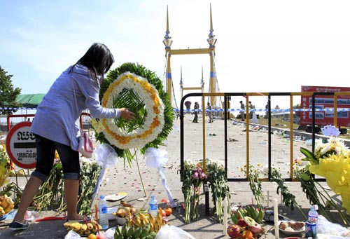 A woman lays flowers as she mourns for the people who died from a stampede near a bridge during a water festival, in Phnom Penh November 24, 2010. [China Daily/Agencies]