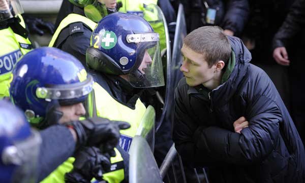 A demonstrator stares at a policeman during a protest, in central London November 24, 2010. British university students Wednesday staged nationwide protests against planned tuition fee increases during which a police van was damaged in central London. [Xinhua]
