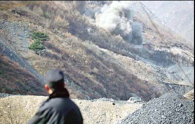 An enforcement officer checks the blasting of three small illegal coal mines on Tuesday in Fangshan district.