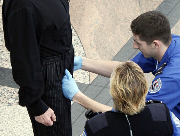 A Transportation Security Agency (TSA) worker (R) runs his hands over the pants of a traveler as another TSA worker (C) looks on during a patdown search at Denver International Airport, the day before Thanksgiving Nov 24, 2010. [China Daily/Agencies] 