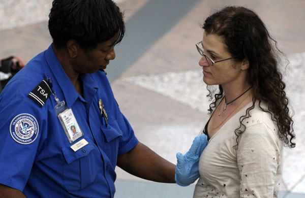  A Transportation Security Agency (TSA) worker (R) runs his hands over the pants of a traveler as another TSA worker (C) looks on during a patdown search at Denver International Airport, the day before Thanksgiving Nov 24, 2010. [China Daily/Agencies]