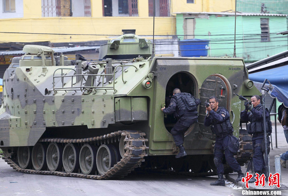 Policemen stand guard as another officer enters an armored Navy vehicle during an operation at Vila Cruzeiro slum in Rio de Janeiro November 25, 2010. Authorities in Rio de Janeiro struggled to control a fifth day of violence apparently orchestrated by drug gang members who have attacked police stations and burned cars in the Brazilian city. [Chinanews.com] 