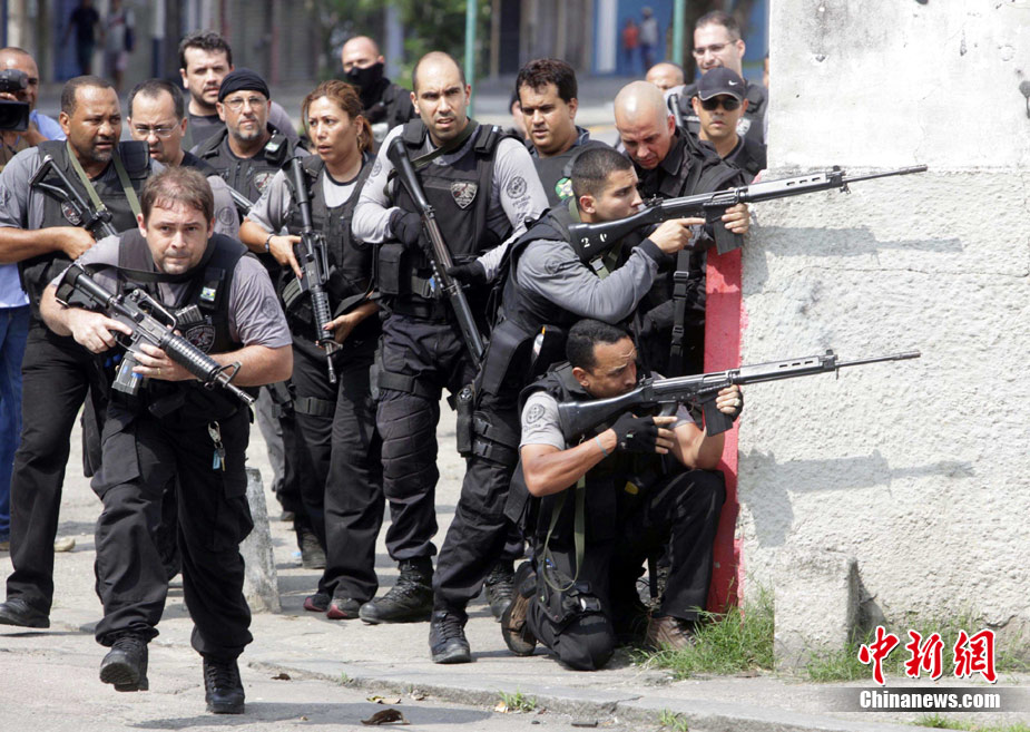 A police officer runs near other officers taking position during a shootout with traffickers during an operation at Vila Cruzeiro slum in Rio de Janeiro November 25, 2010. [Chinanews.com] 