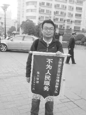 A young man holding a banner that reads 'Not for the People' can regularly be seen outside government offices in Wuxi City, Jiangsu Province. The message is directed at the local labor security authority.