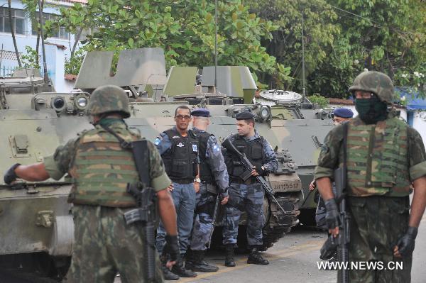 Police and soldiers gather in front of tanks in Vila Cruzeiro, north of Rio de Janeiro, Brazil, Nov. 26, 2010. Some 800 soldiers and police with tanks carried out the operation against heavily-armed gangsters to control the worsened situation. [Song Weiwei/Xinhua]