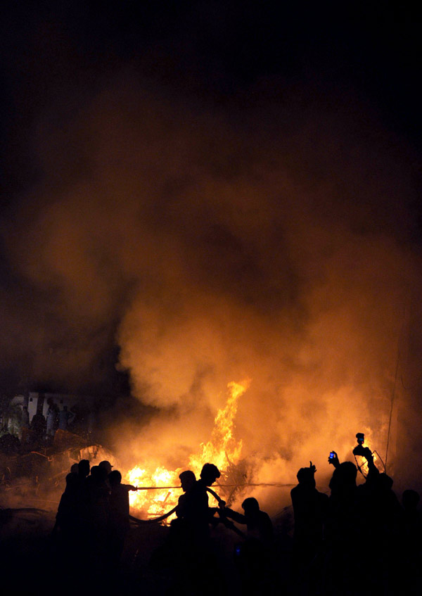 Pakistani volunteers struggle to extinguish the fire at the site of a plane crash in southern Pakistani port city of Karachi on Nov. 28, 2010. At least 18 people including 10 on the ground were killed as a Russian-made IL 76 cargo plane crashed in a residential area near the Karachi airport in southern Pakistan early Sunday morning. [Xinhua]