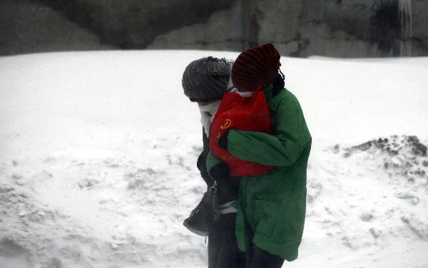 People walk against strong wind in Jilin City, northeast China&apos;s Jilin Province, Nov. 27, 2010. Snowfall hit most parts of the province from Friday night. Local meteorologic authority has issued a blue alarm against cold wave Saturday morning. [Xinhua]