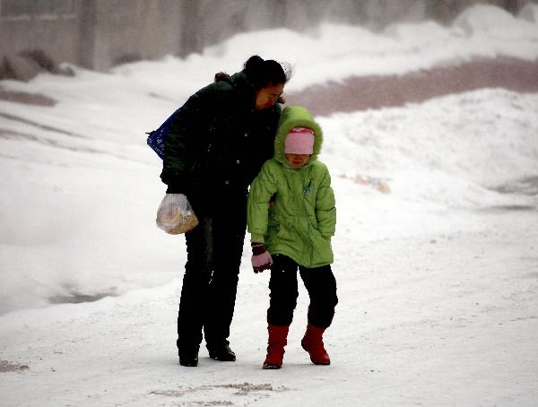 People walk against strong wind in Jilin City, northeast China&apos;s Jilin Province, Nov. 27, 2010. Snowfall hit most parts of the province from Friday night. Local meteorologic authority has issued a blue alarm against cold wave Saturday morning. [Xinhua]