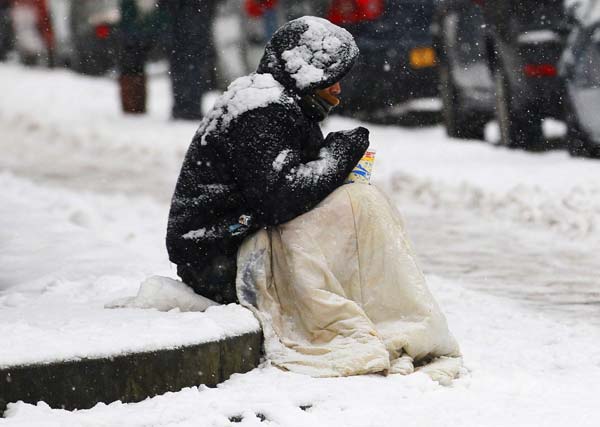 A beggar sits in the snow in Edinburgh, Scotland November 28, 2010. Freezing temperatures were recorded around the country after heavy overnight snowfalls, local media reported. [Xinhua/Reuters] 