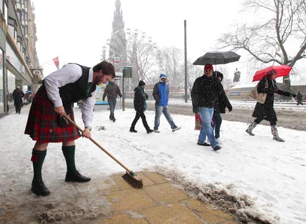 Duncan Wilson, a tartan salesperson, clears the snow away from the front of his store in Edinburgh, Scotland November 28, 2010. Freezing temperatures were recorded around the country after heavy overnight snowfalls, local media reported. [Xinhua/Reuters] 