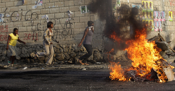 Haitians run on the street while tires burn during a protest in Port-au-Prince November 28, 2010. [Xinhua]