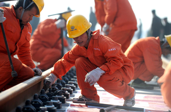 Workers lay down tracks for the Shijiazhuang-Wuhan high speed rail in Xuchang, Central China's Henan province, Nov 29, 2010.