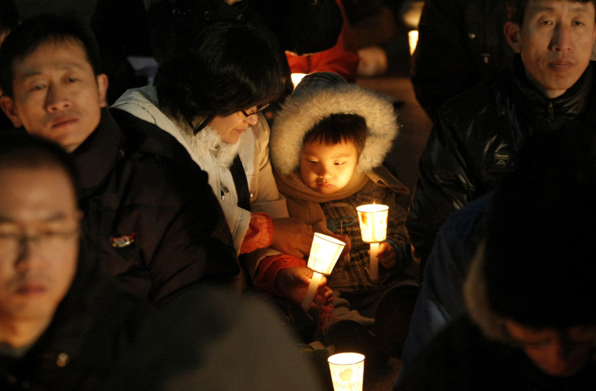 People hold candles to express their wish of peace during a rally against the joint military exercise of South Korea and the United States in Seoul, capital of South Korea, on Nov. 29, 2010. [Xinhua]