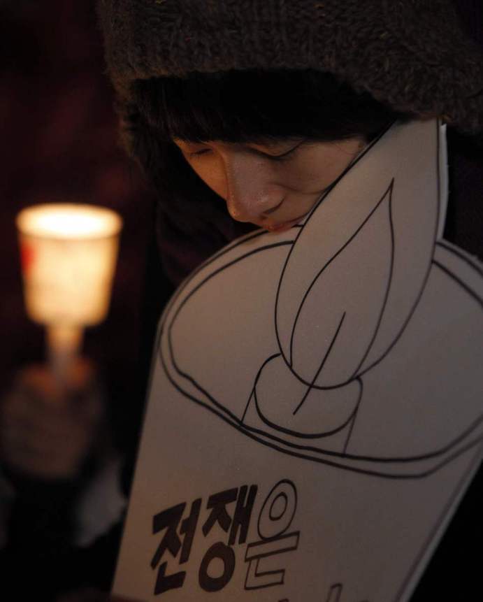 People hold candles to express their wish of peace during a rally against the joint military exercise of South Korea and the United States in Seoul, capital of South Korea, on Nov. 29, 2010. [Xinhua]