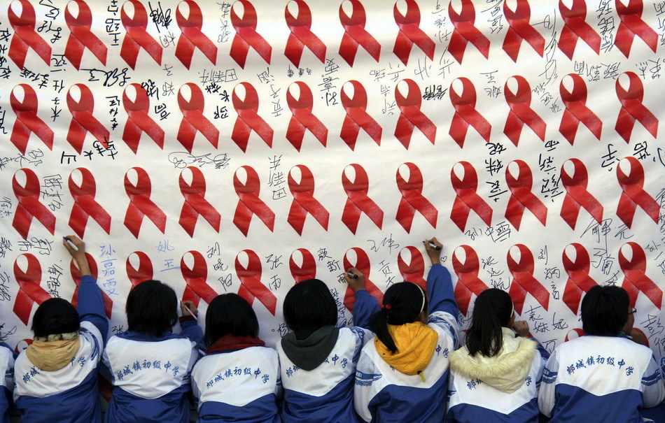 Pupils of Tongkuang No.2 Primary School sign on a board during a publicity activity on AIDS prevention in Dexing City of east China&apos;s Jiangxi Province, Nov. 30, 2010, a day ahead of the World AIDS Day. [Xinhua]