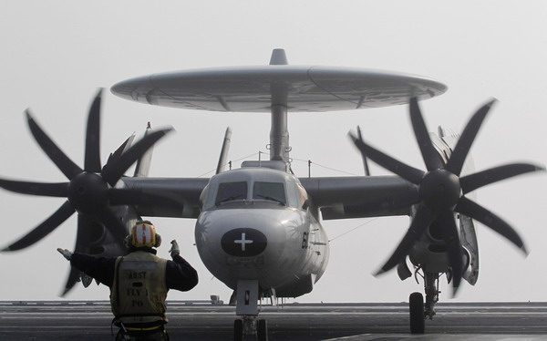 A flight deck crew member guides an E-2C Hawkeye as it lands on the US Navy&apos;s USS George Washington aircraft carrier during joint military drills between the US and ROK in the West Sea November 30, 2010. 