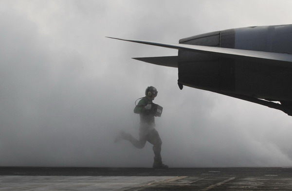 A flight deck crew runs as he prepares a US Navy F/A-18F Super Hornet for take-off on the US Navy&apos;s USS George Washington aircraft carrier during a joint military drills between the US and ROK in the West Sea November 30, 2010. [China Daily/Agencies]