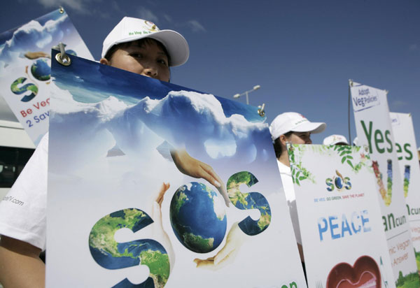 Activists of The Supreme Master Ching Hai International Organization hold signs urging people to turn vegetarian as they believe it will save the planet, in Cancun Nov 29, 2010. [China Daily/Agencies]