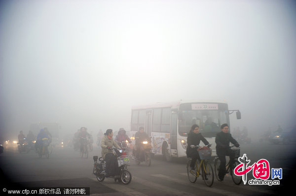 Pepople and vehicles across a road in dense fog in Xingtai, North China&apos;s Hebei province on the morning of Dec 1, 2010. Heavy fog shrouded China&apos;s central and eastern regions Wednesday morning, causing road closures in some areas. [CFP]