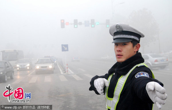 A policeman directs the traffic on a road in dense fog in Xingtai, North China&apos;s Hebei province, on the morning of Dec 1, 2010. [CFP]