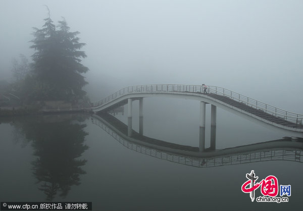 A student walks on a bridge in dense fog in Nantong, Southeast China&apos;s Jiangsu province on the morning of Dec 1, 2010. [CFP]