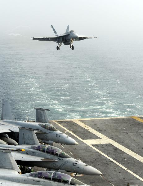 A jet fighter is about to land on the aircraft carrier USS George Washington during a joint military exercise conducted by South Korea and the United States in tense waters west of the divided Korean Peninsula on Nov. 30, 2010. [Pool/Xinhua]