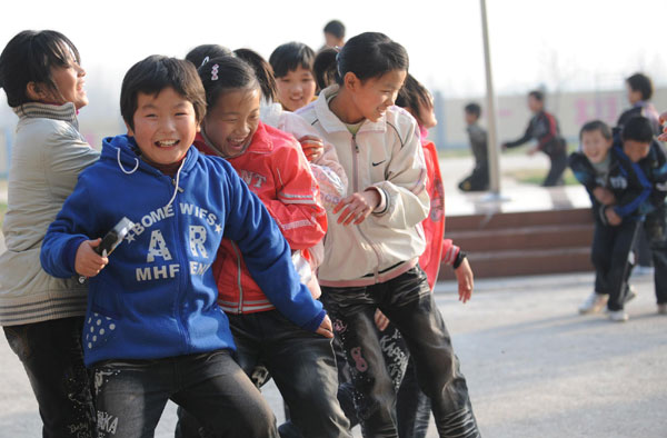 Children play the hawk-and-chicken game with their teachers at a school for orphans who lost their parents to AIDS in Shangcai county, Henan province on Nov 30, 2010. [Photo/Xinhua] 