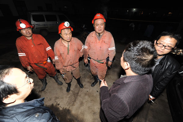 Rescue workers discuss the plan to save seven trapped miners at the scene in Xiangtan city, Central China's Hunan province on Dec 1, 2010. 