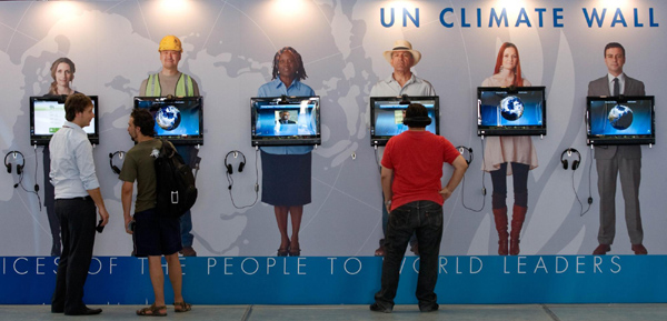 Visitors look at the UN Climate Wall, a photo exhibition, during the United Nations Climate Change Conference in Cancun, a resort city in Mexico, Dec 1, 2010. 