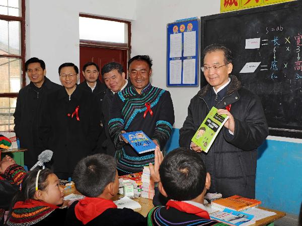 Chinese Premier Wen Jiabao (1st R) presents books to the orphans whose parents died of AIDS at a primary school in Sikai Town, Zhaojue County of Liangshan Yi Autonomous Prefecture, southwest China&apos;s Sichuan Province, Dec.1, 2010. Visiting poverty-stricken area, Wen urged a better incorporation of AIDS control work with economic development in less developed areas. [Xinhua]