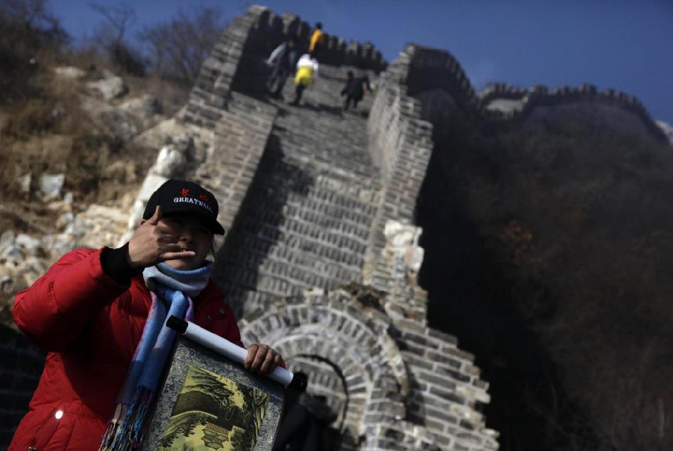 A woman tries to sell paintings to tourists as she stands on the Great Wall at Simatai, located in the outskirts of Beijing December 1, 2010. [China Daily]