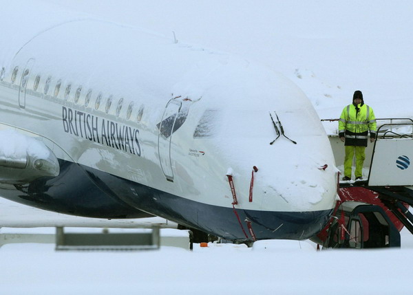 An engineer stands next to a snow covered British Airways aeroplane at Edinburgh Airport, in Edinburgh, Scotland December 2, 2010. [China Daily/Agencies]