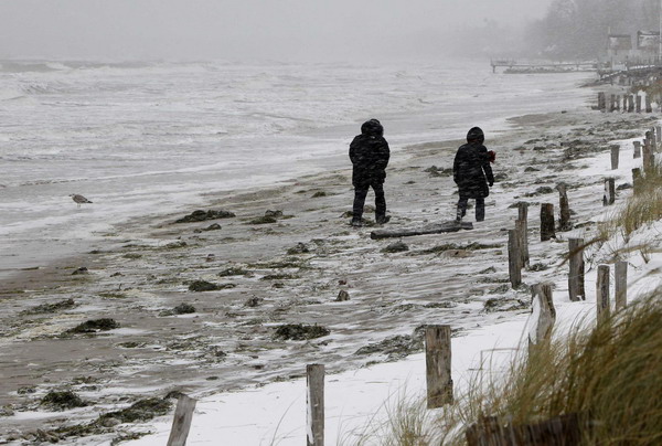 People brave a strong snow storm as they stroll along the icy shore on the Baltic Sea near Scharbeutz December 2, 2010.[China Daily/Agencies]