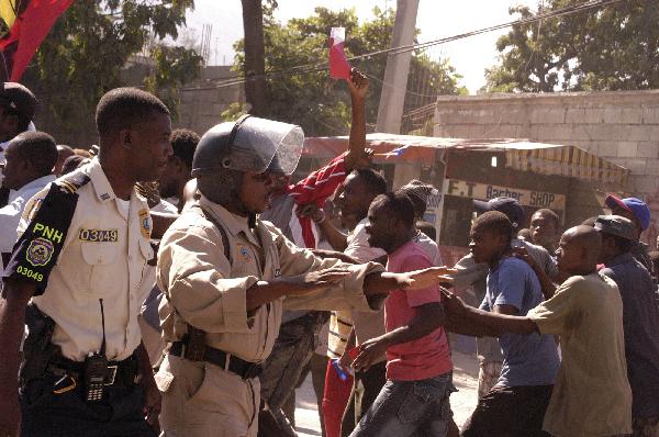 Policemen try to control people during a protest that around 2,000 Haitians marched demanding a rerun of Sunday&apos;s elections, in Port-au-Prince, Haiti&apos;s capital, on Dec. 2, 2010. [Xinhua]