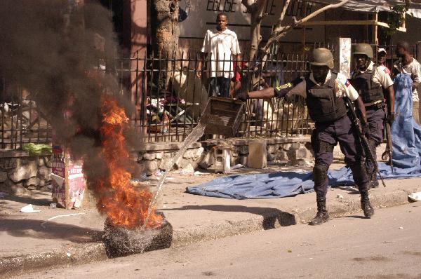 A policeman tries to put out a burning tire during a protest that around 2,000 Haitians marched demanding a rerun of Sunday&apos;s elections, in Port-au-Prince, Haiti&apos;s capital, on Dec. 2, 2010. [Xinhua]