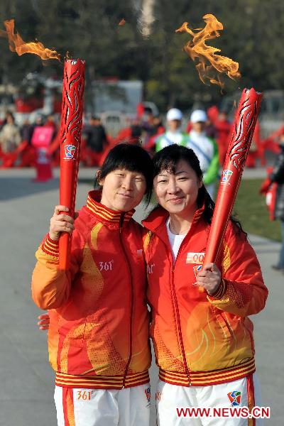 Torch bearers Wang Ruixue (L) and Han Jie take a photo during the torch relay for Guangzhou 2010 Asian Para Games held at the Tian'anmen Square in Beijing, capital of China, Dec. 4, 2010. [Xinhua/Liu Dawei]