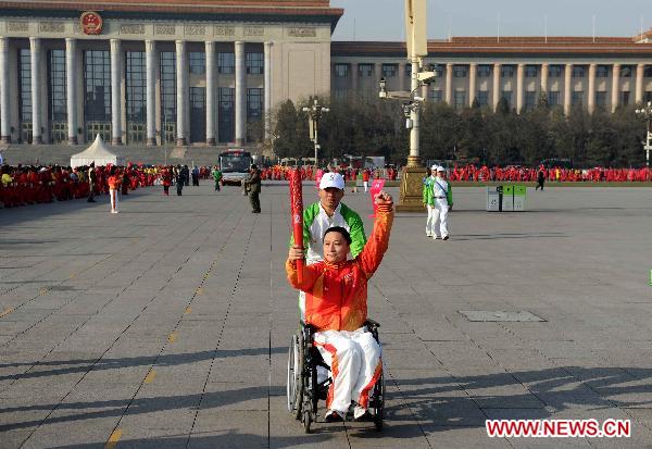 Torch bearer Chen Haijiang relays the torch in the wheelchair during the torch relay for Guangzhou 2010 Asian Para Games held at the Tian'anmen Square in Beijing, capital of China, Dec. 4, 2010. (Xinhua/Liu Dawei)