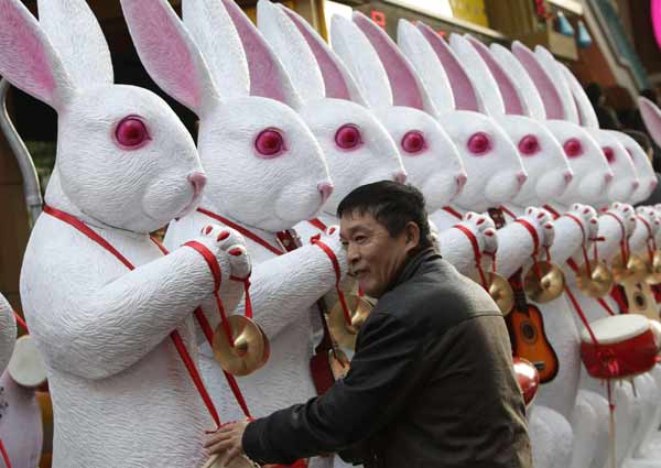 A resident plays in front of rabbit sculptures at an entrance of a market in Beijing Dec 5, 2010. According to the Chinese lunar calendar, the year of the rabbit begins on February 3, 2011. [China Daily/Agencies]