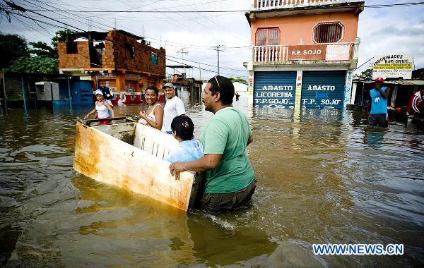 A woman is carried through the waters in an old refrigerator on a flooded road in Higuerote, Miranda, Venezuela. Dec. 5, 2010. [Xinhua] 