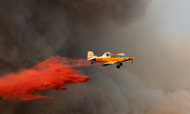 A fire-fighting aircraft drops water over a forest fire near Isfiya, on Mount Carmel, near Haifa, north Israel, Dec. 5, 2010. After more than three days&apos; arduous battle, Israeli firefighting authority announced Sunday afternoon that it had fully contained the inferno, according to local news service Ynet. [Xinhua]