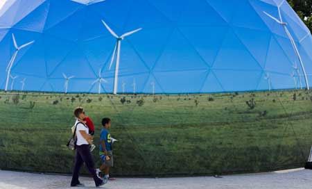 A family passes by one of the stands promoting green energy at the Climate Village in Cancun, Mexico, Saturday. UN climate talks in Cancun ran into a storm Friday as a deepening split emerged over the future of the carbon-cutting Kyoto Protocol. 